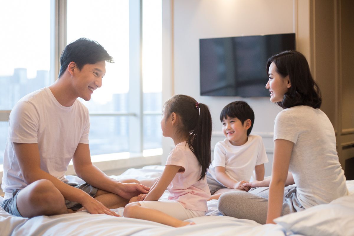 A fmaily with their children relaxing in the bedroom of their condo